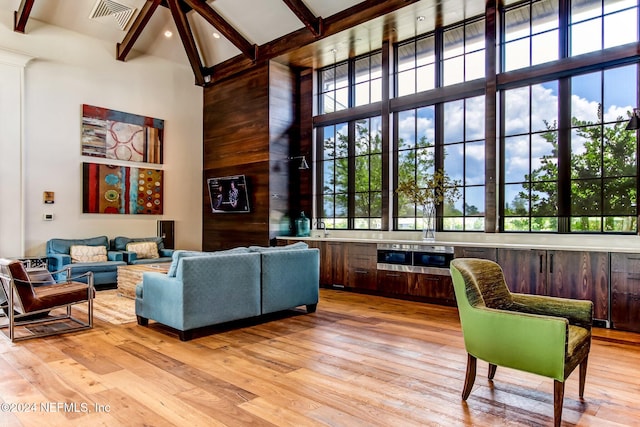 interior space with beam ceiling, light hardwood / wood-style flooring, and high vaulted ceiling