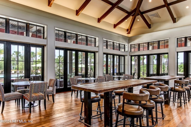 dining room featuring beamed ceiling, light hardwood / wood-style flooring, high vaulted ceiling, and french doors