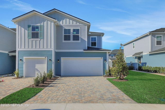 view of front of house featuring an attached garage, decorative driveway, a front lawn, and board and batten siding