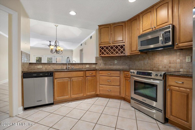 kitchen with decorative backsplash, appliances with stainless steel finishes, an inviting chandelier, and sink