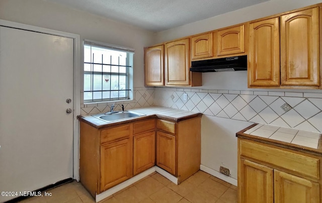 kitchen featuring tasteful backsplash, tile counters, light tile patterned floors, and sink