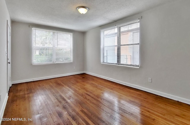 spare room with hardwood / wood-style flooring, plenty of natural light, and a textured ceiling