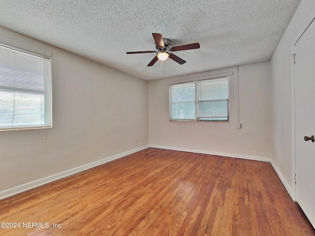 spare room with a textured ceiling, hardwood / wood-style flooring, plenty of natural light, and ceiling fan