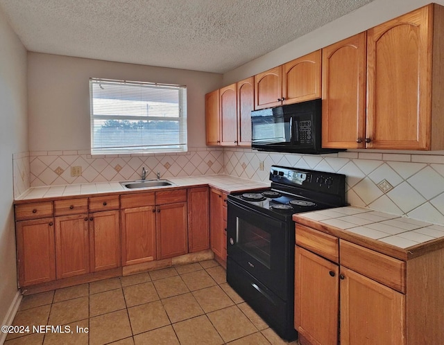 kitchen featuring tile counters, sink, backsplash, light tile patterned floors, and black appliances