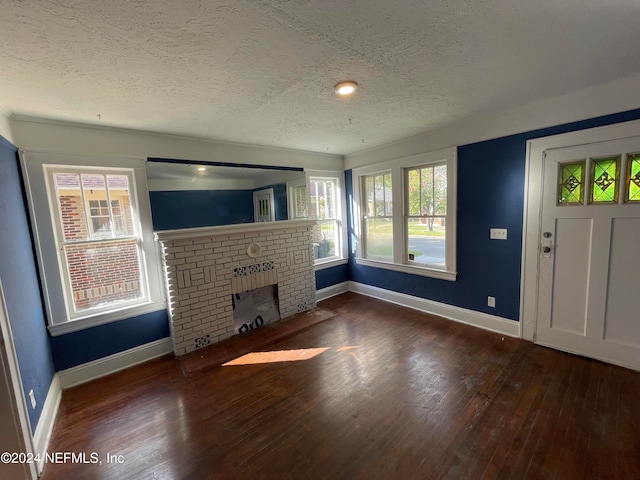 unfurnished living room featuring a fireplace, a textured ceiling, and dark hardwood / wood-style floors