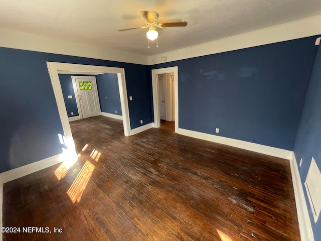 spare room featuring ceiling fan, dark wood-type flooring, and a textured ceiling