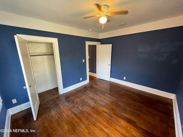 unfurnished bedroom featuring ceiling fan, a closet, and dark wood-type flooring