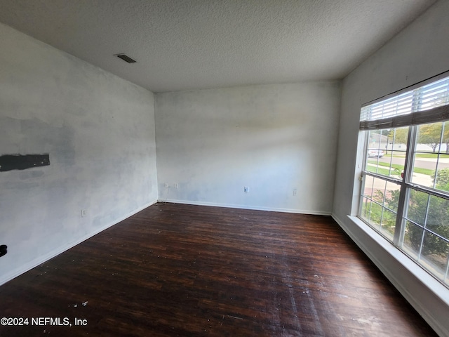 spare room featuring a textured ceiling and dark wood-type flooring