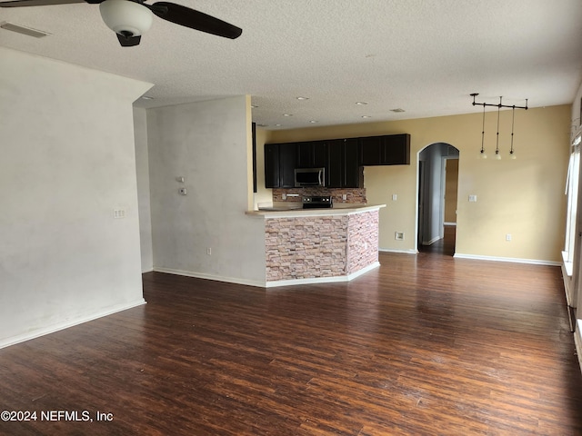 unfurnished living room with a textured ceiling, ceiling fan, and dark wood-type flooring