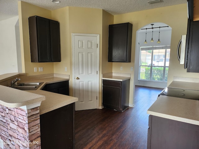 kitchen featuring kitchen peninsula, a textured ceiling, dark wood-type flooring, sink, and range