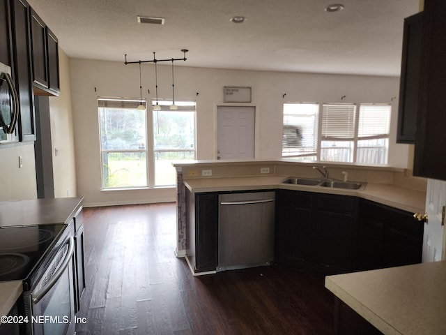 kitchen with dark hardwood / wood-style flooring, dark brown cabinetry, stainless steel appliances, sink, and pendant lighting