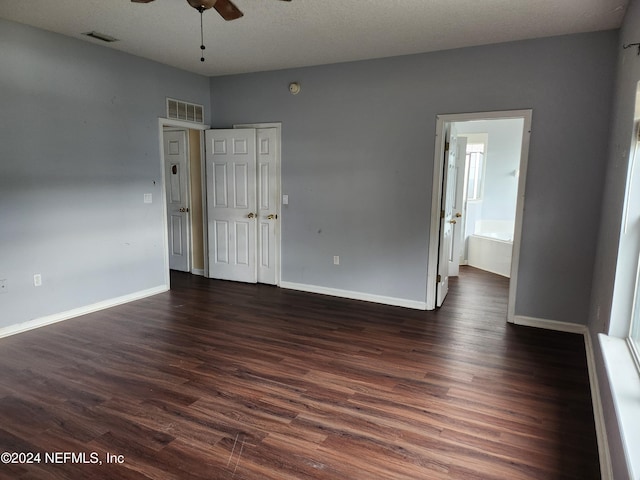 empty room with a textured ceiling, dark hardwood / wood-style floors, and ceiling fan