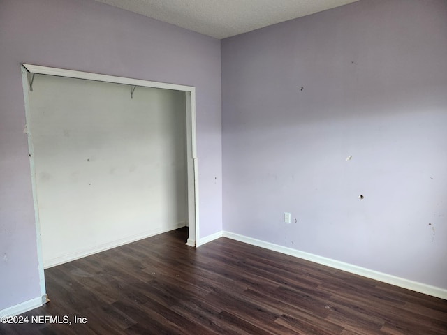 unfurnished bedroom featuring dark hardwood / wood-style floors, a textured ceiling, and a closet