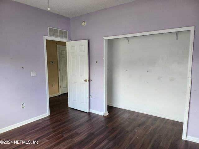 unfurnished bedroom featuring a textured ceiling, a closet, and dark hardwood / wood-style floors