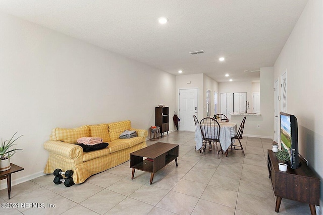 living room with light tile patterned floors, a textured ceiling, and sink