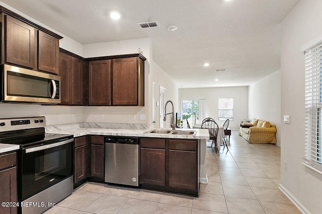 kitchen featuring appliances with stainless steel finishes, dark brown cabinets, a textured ceiling, sink, and light tile patterned floors