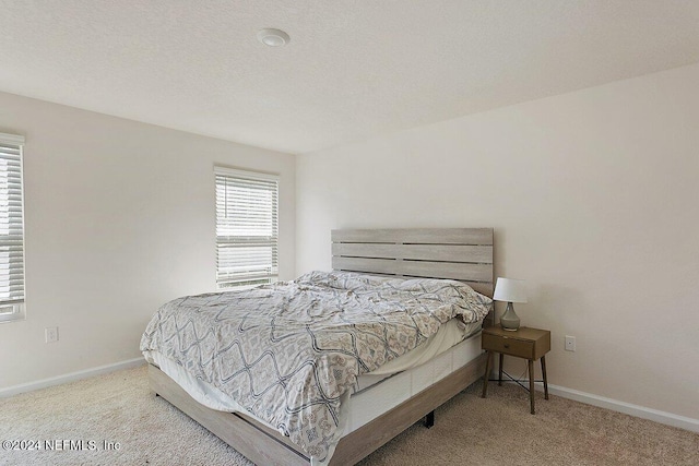 bedroom with light carpet and a textured ceiling