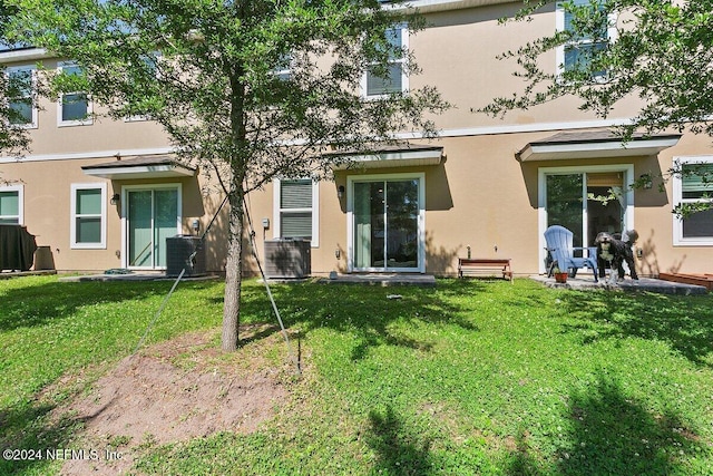 rear view of house featuring a lawn and central air condition unit