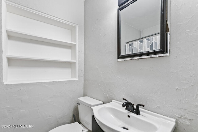 bathroom featuring toilet, vanity, and built in features