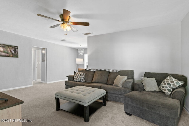 carpeted living room featuring ceiling fan with notable chandelier