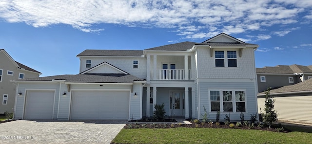 view of front of property with a garage, a front lawn, decorative driveway, and a balcony