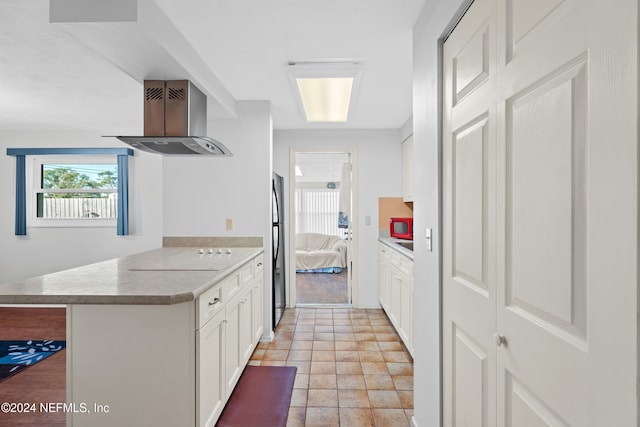 kitchen with white cabinets, a kitchen breakfast bar, refrigerator, ventilation hood, and kitchen peninsula