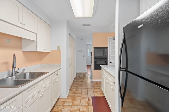 kitchen featuring black appliances, white cabinets, and sink