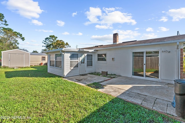 rear view of house with a shed, a yard, and a patio