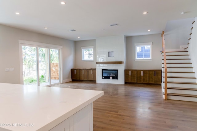 unfurnished living room with stairs, a fireplace, wood finished floors, and recessed lighting