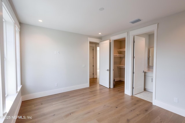 unfurnished bedroom with baseboards, visible vents, a spacious closet, light wood-type flooring, and recessed lighting