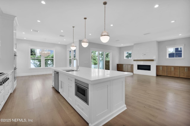 142 Ocean Blvd, Atlantic Beach, FL 32233 - kitchen featuring appliances with stainless steel finishes, a fireplace, light wood finished floors, recessed lighting, and a kitchen island with sink