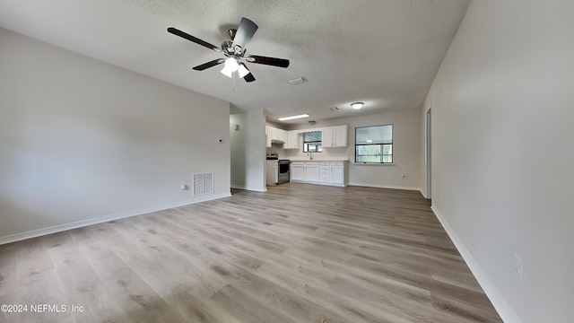 unfurnished living room featuring ceiling fan, light hardwood / wood-style floors, and a textured ceiling