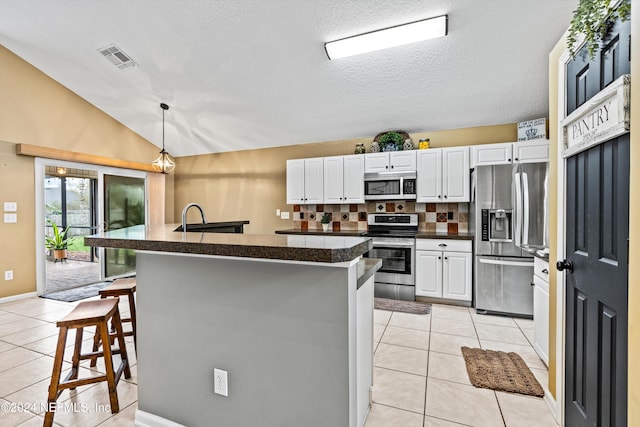 kitchen featuring backsplash, lofted ceiling, a breakfast bar, white cabinets, and appliances with stainless steel finishes