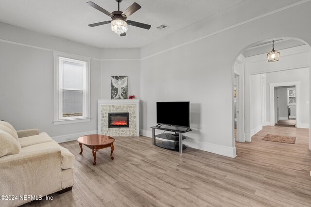 living room featuring a tile fireplace, ceiling fan, and light hardwood / wood-style floors