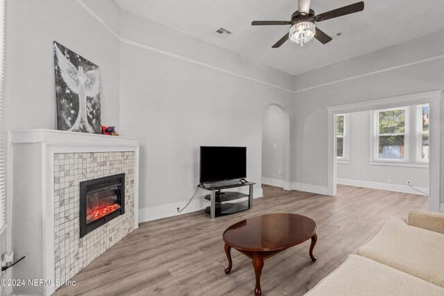 living room featuring ceiling fan, a fireplace, and light hardwood / wood-style flooring