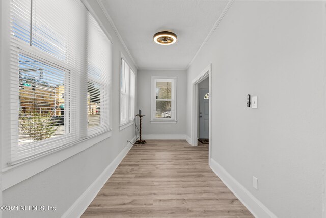 hall with light hardwood / wood-style floors and ornamental molding