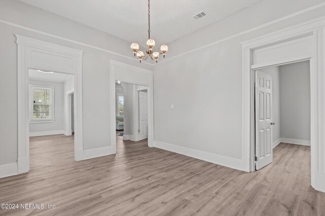 unfurnished room with a chandelier and light hardwood / wood-style flooring