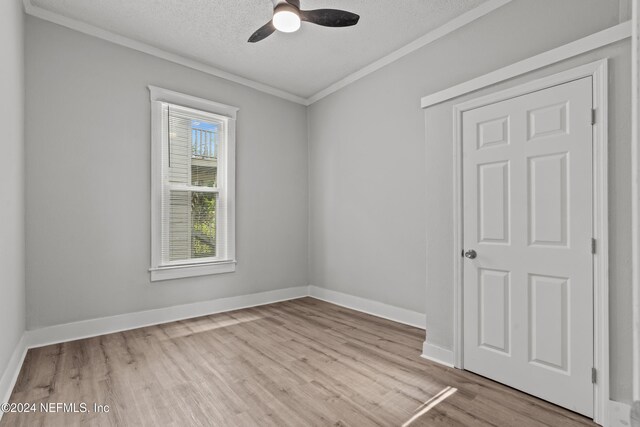 empty room with crown molding, light hardwood / wood-style flooring, ceiling fan, and a textured ceiling