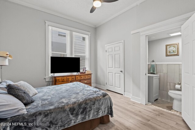 bedroom featuring ensuite bathroom, crown molding, ceiling fan, light wood-type flooring, and a textured ceiling