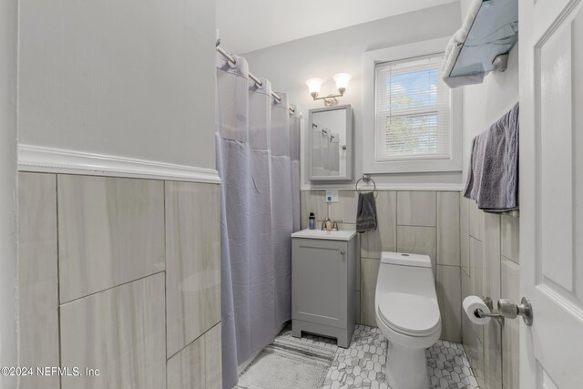 bathroom featuring tile patterned floors, vanity, tile walls, toilet, and curtained shower