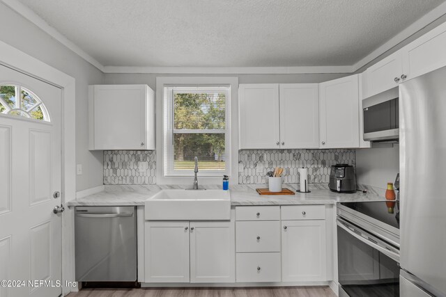 kitchen with appliances with stainless steel finishes, white cabinetry, and a wealth of natural light