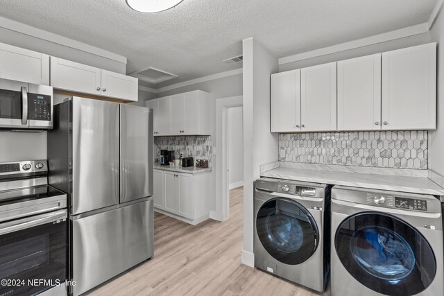 laundry area with washing machine and clothes dryer, crown molding, a textured ceiling, and light wood-type flooring