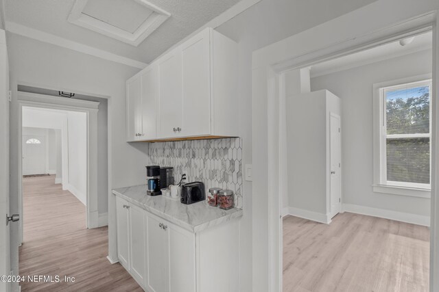 kitchen with light hardwood / wood-style floors, light stone countertops, white cabinetry, and tasteful backsplash