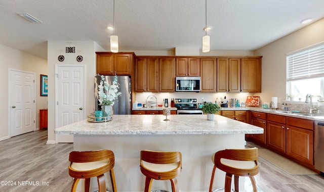 kitchen featuring sink, a kitchen island, pendant lighting, and appliances with stainless steel finishes