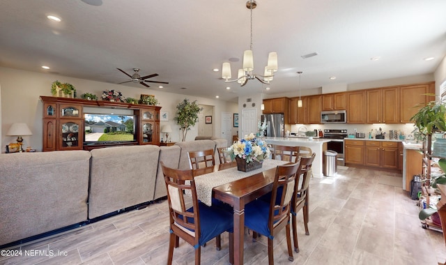 dining room featuring ceiling fan with notable chandelier and light hardwood / wood-style flooring