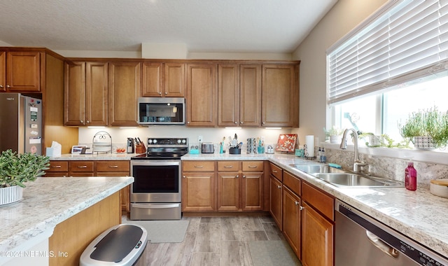 kitchen featuring a textured ceiling, sink, appliances with stainless steel finishes, and light hardwood / wood-style flooring