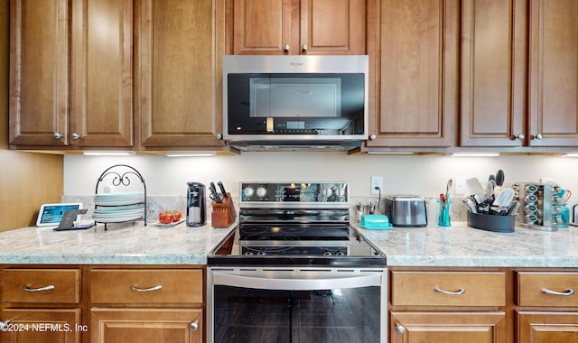 kitchen with appliances with stainless steel finishes and light stone counters