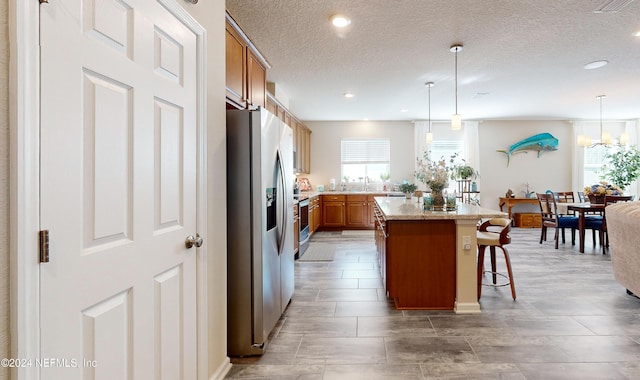 kitchen with pendant lighting, a kitchen breakfast bar, stainless steel fridge, and a kitchen island