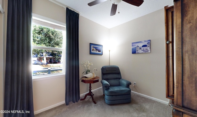 living area featuring ceiling fan, light colored carpet, and a healthy amount of sunlight