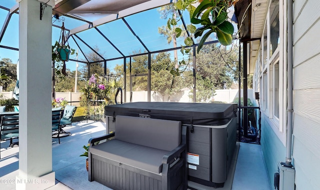 view of patio featuring glass enclosure and a hot tub